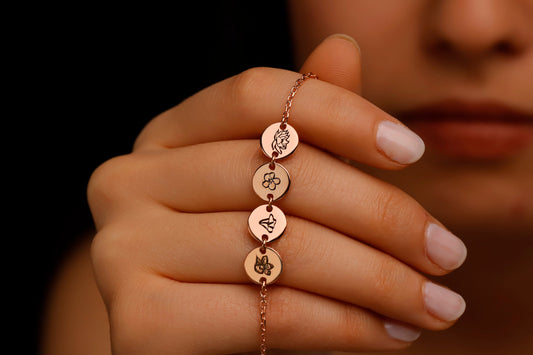 Rose gold bracelet with circular charms on a hand against a dark background