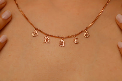 Personalized name necklace featuring dangle Gothic Old English letters spelling 'GRACE' on a delicate chain.