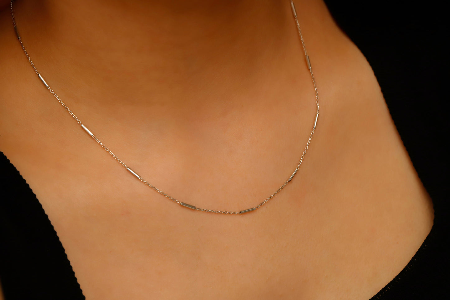 Gold necklace on a person's neck against a black background