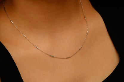 Gold necklace on a person's neck against a black background