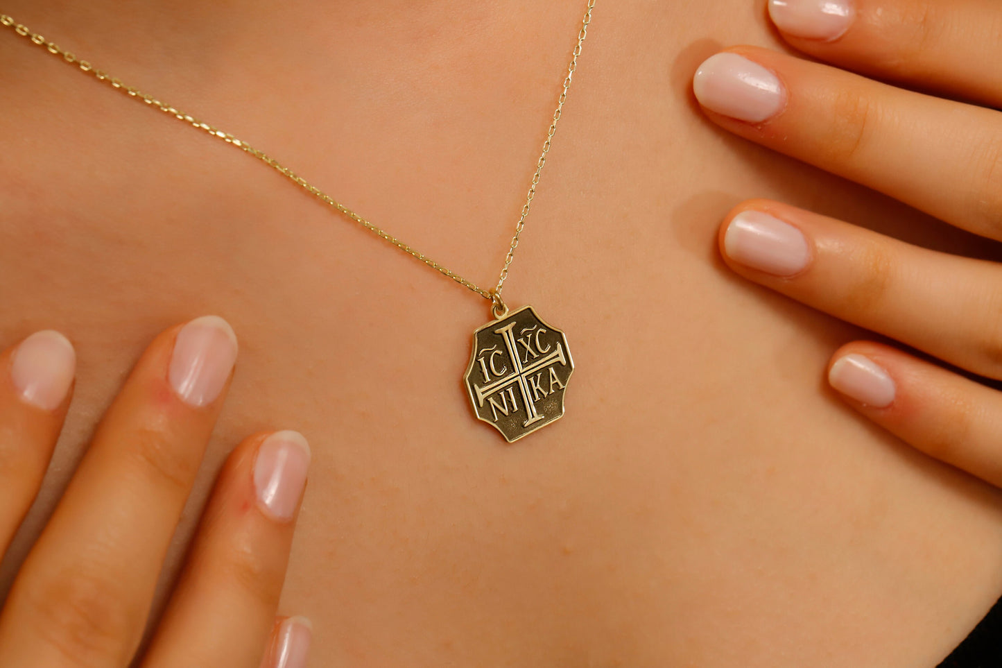 Gold necklace with a hexagonal pendant on a person's chest
