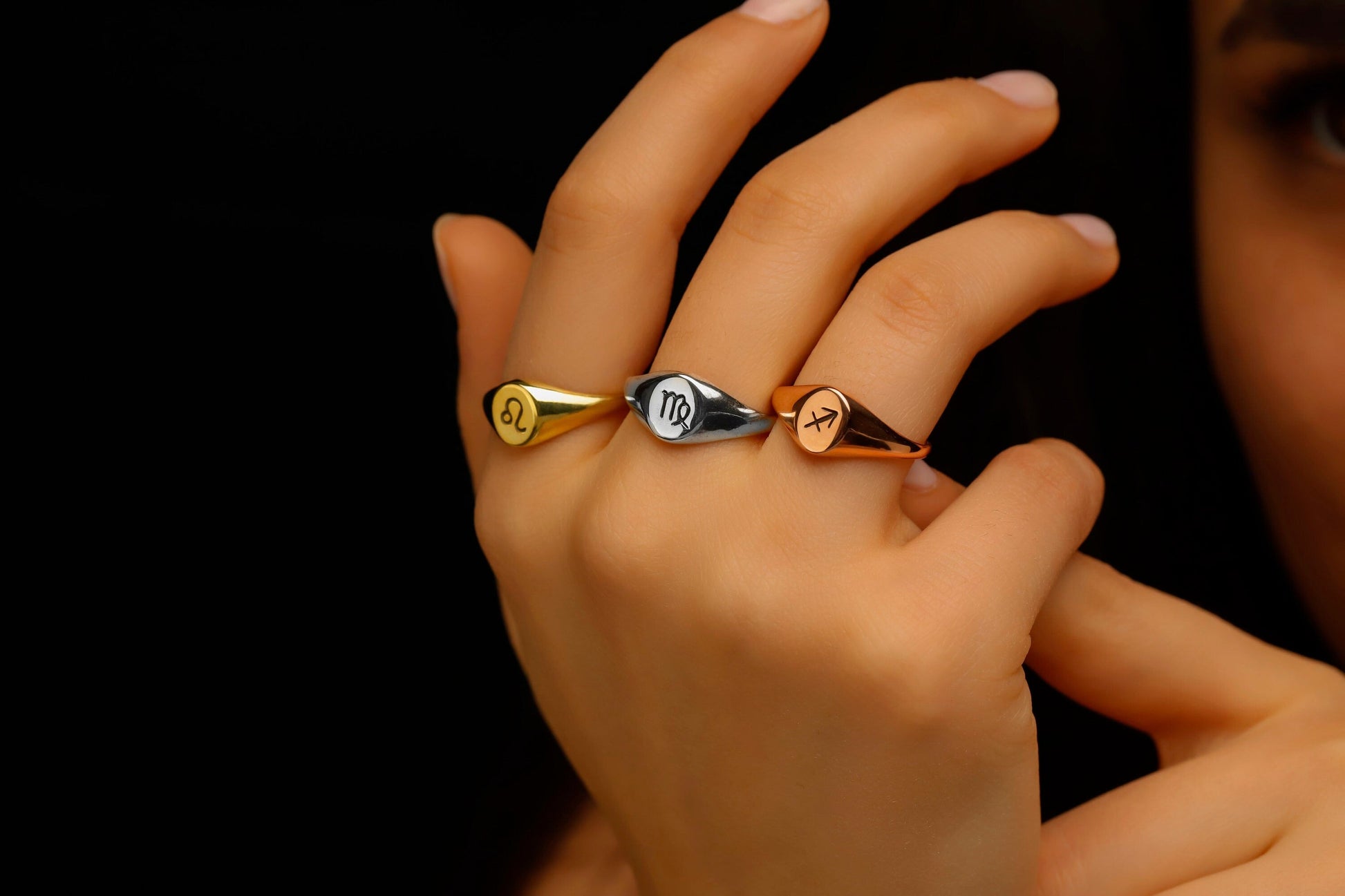 Three rings with different designs on a hand against a black background