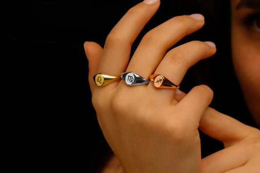 Three rings with different designs on a hand against a black background