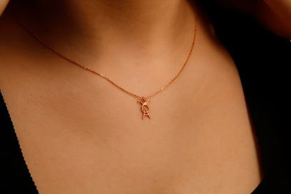 Rose gold necklace with a small pendant on a person's neck against a dark background