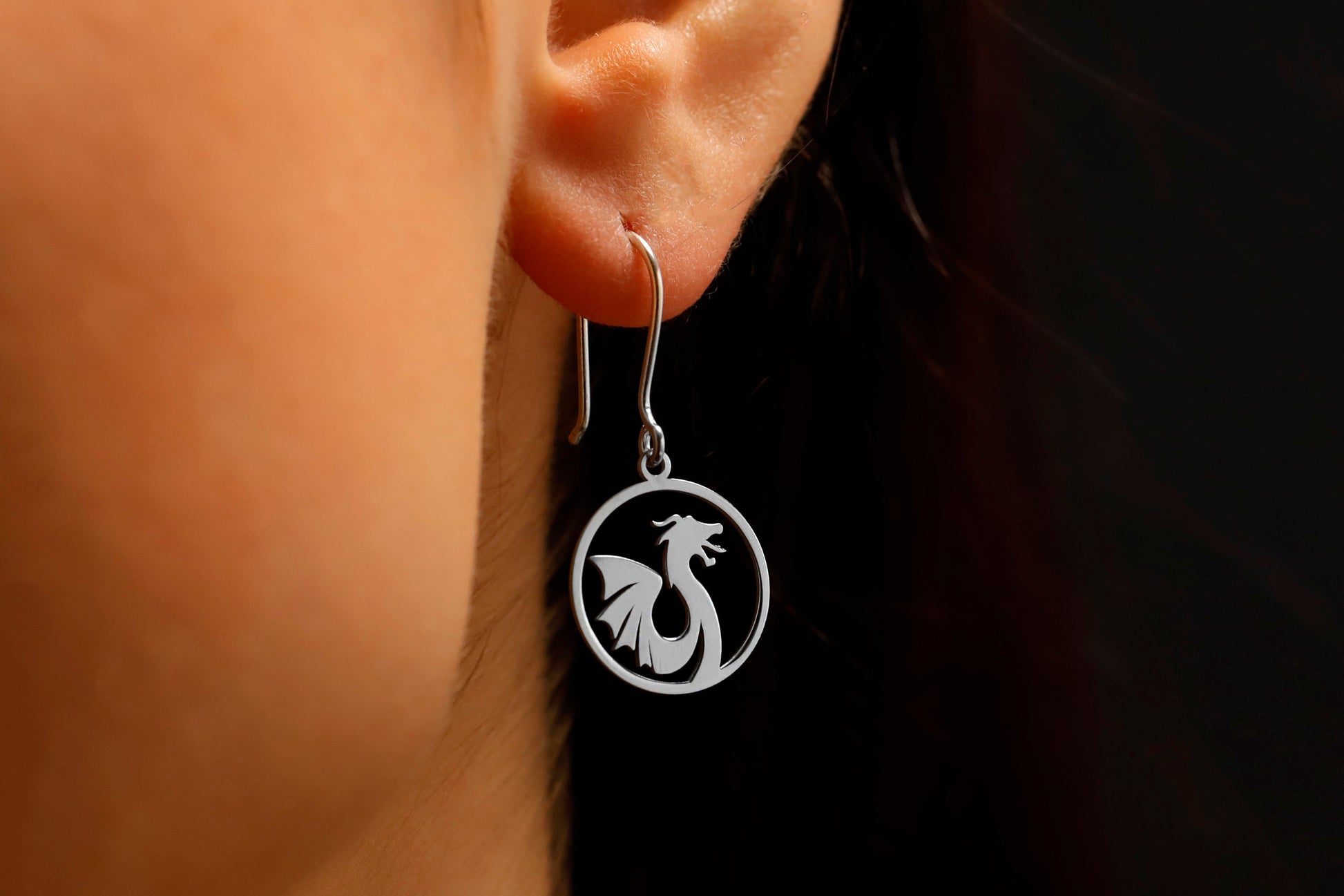 Silver earring with dragon design worn by a person