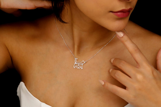 Woman wearing a silver necklace with a cat pendant on a dark background
