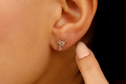 A close-up image of a person wearing a small rose hoop earring in their left ear.