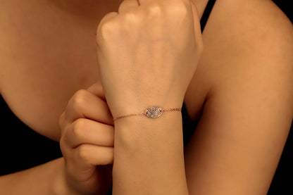 A rose gold-colored bracelet with a fingerprint engraving on a disc, displayed on a person's wrist.