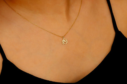 A gold monogram necklace with the initial 'S' displayed on a person's hand, highlighting the necklace's elegant cursive script design.