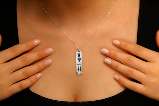 Person wearing a necklace with a pendant featuring question marks on a black background