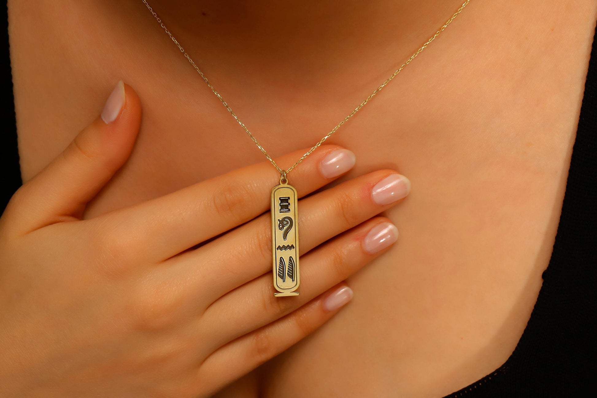 Gold necklace with a pendant worn by a person