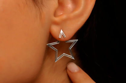 Star-shaped silver earring worn by a person with a blurred background