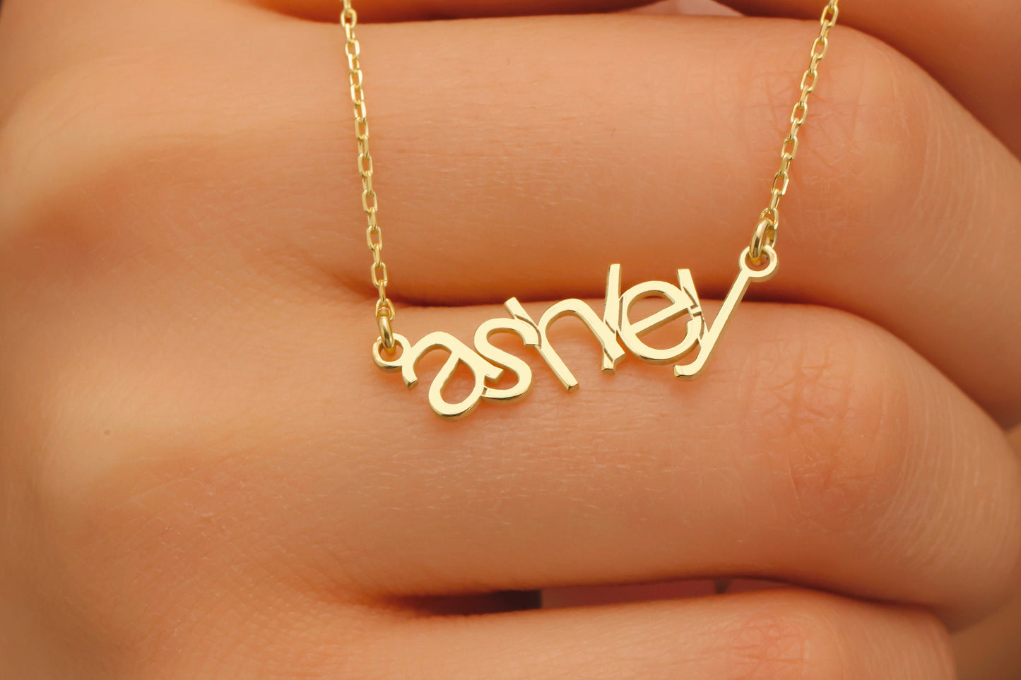 Gold necklace with 'ashley' pendant on a hand