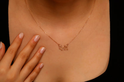 Rose gold necklace with a small pendant on a person's neck against a black background