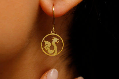 Gold earring with dragon design worn on an ear against a dark background