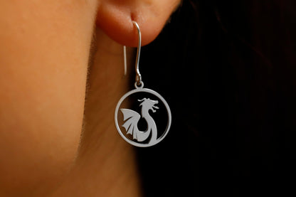 Silver earring with dragon design worn by a person against a dark background