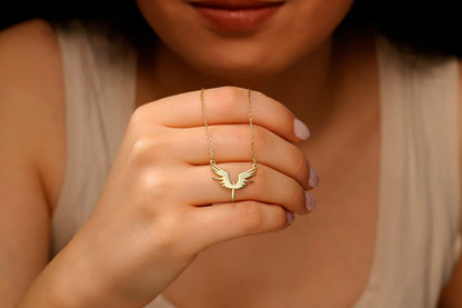 A dainty phoenix necklace with gold wings pendant on a hand, showcasing the delicate and elegant design.