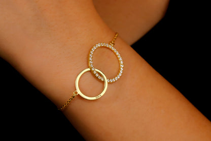 Gold bracelet with interlocking rings on a wrist against a black background