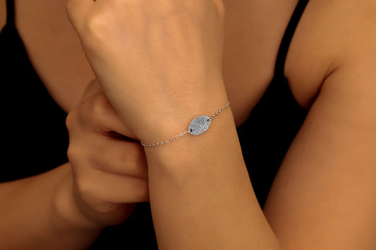 A 925 sterling silver bracelet with a fingerprint engraving on a disc, displayed on a person's wrist.