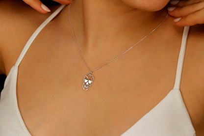 A close-up image of a person wearing a sterling silver necklace with a sugar skull pendant.