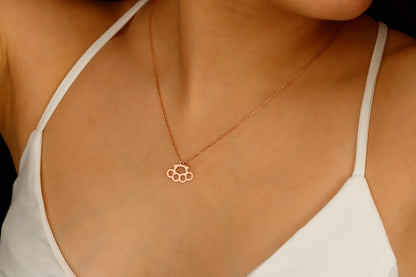 A close-up image of a gold-filled necklace with a brass knuckle design being worn on a person's finger.