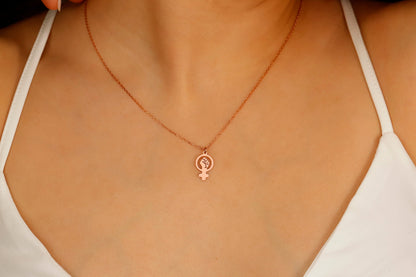 A rose gold necklace with a Venus symbol pendant on a model