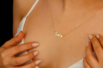 A close-up image of a woman's neck displaying a dainty gold necklace with the name 'Sophie' written in a magical Harry P. font.