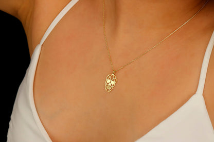 A close-up image of a person wearing a gold necklace with a sugar skull pendant.