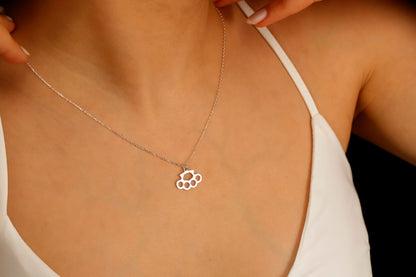 A close-up image of a gold-filled necklace with a brass knuckle design being worn on a person's finger.