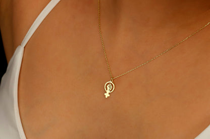 A gold necklace with a Venus symbol pendant on a model