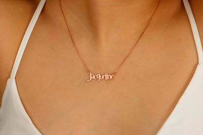 A close-up image of a woman's neck displaying a dainty rose necklace with the name 'Jacqueline' written in a magical Harry P. font.