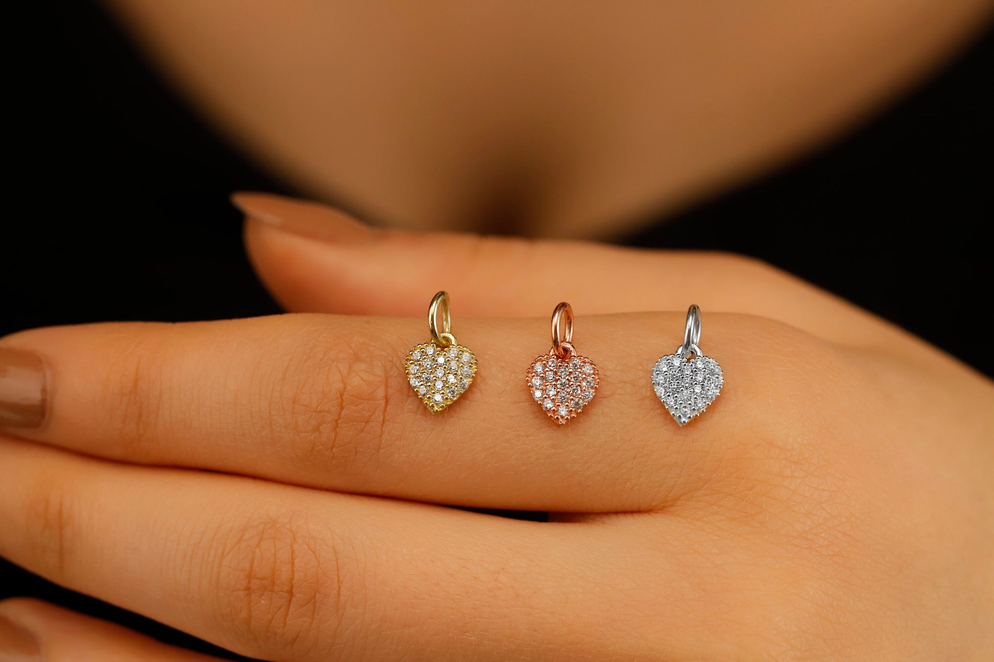 Heart-shaped earrings displayed on a hand against a dark background