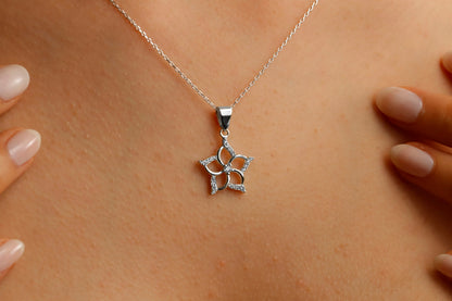 A close-up image of a woman wearing a silver necklace with a star-shaped pendant.