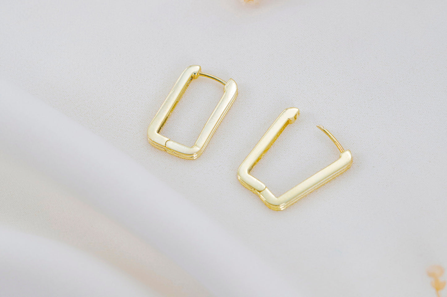 Gold hoop earrings on a light gray background