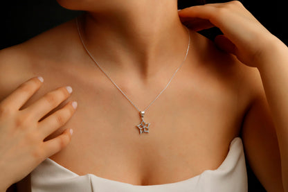 A close-up image of a woman wearing a silver necklace with a star-shaped pendant.