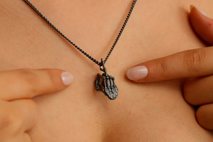 A close-up image of a person's neck wearing a 3D skeleton middle finger sign necklace in silver color with a curb chain.