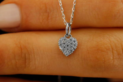 Heart-shaped silver pendant with clear stones on a hand