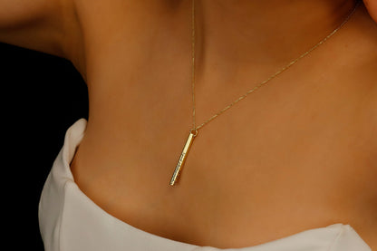 Three necklace with long bars in gold on a model with a dark background.