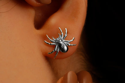A close-up image of a person wearing a 3D spider stud earring made of gold-filled or sterling silver.