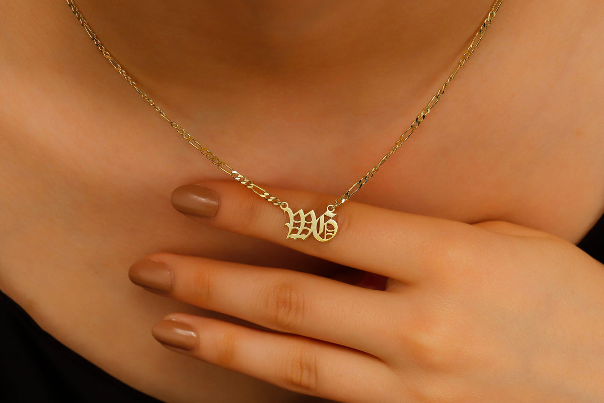 Gold necklace with initials worn by a person