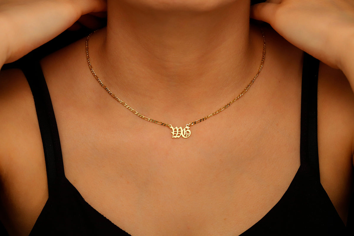Gold necklace with a pendant on a person wearing a black top.