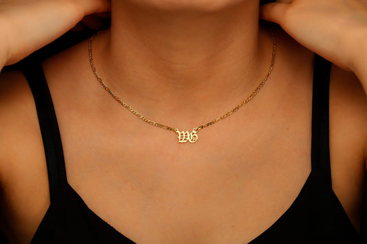 Gold necklace with a pendant on a person wearing a black top.
