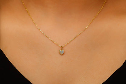 Gold necklace with a heart-shaped pendant on a person's neck