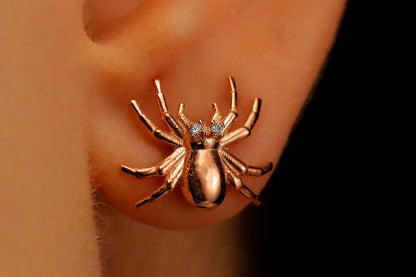 A close-up image of a person wearing a 3D spider stud earring made of gold-filled or sterling silver.