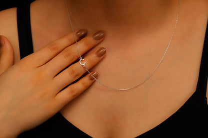 A close-up image of a dainty sideways initial necklace worn by a person, with a hand adjusting the necklace.
