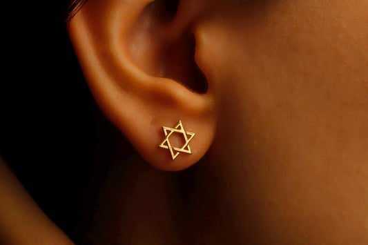 Close-up image of a person wearing a gold-filled David Star earring.