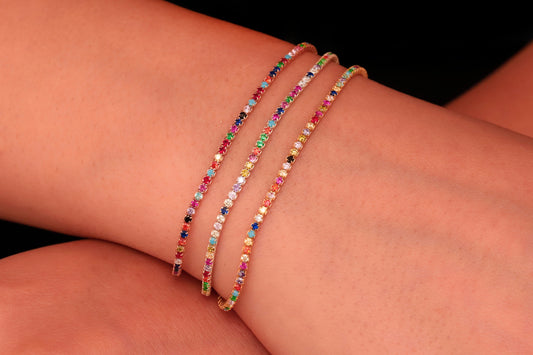 A multicolored minimalist dainty bead bracelet with a gold-colored metal clasp, displayed on a white surface.