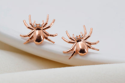 A close-up image of a person wearing a 3D spider stud earring made of gold-filled or sterling silver.