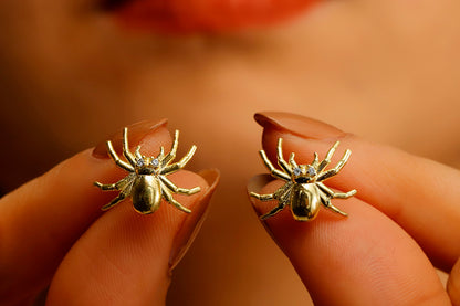 A close-up image of a person wearing a 3D spider stud earring made of gold-filled or sterling silver.