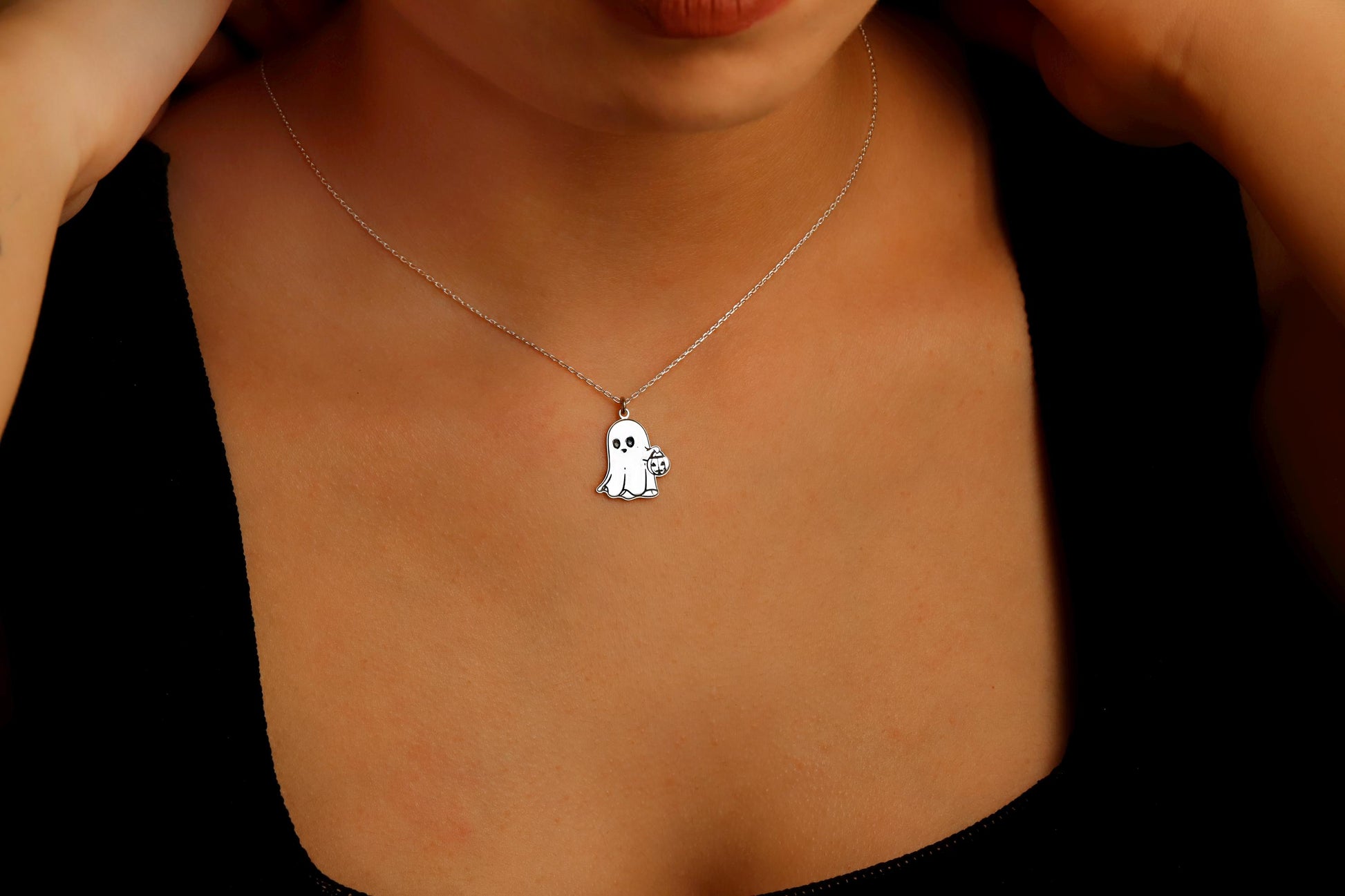 Necklace with a small pendant on a person's neck against a dark background